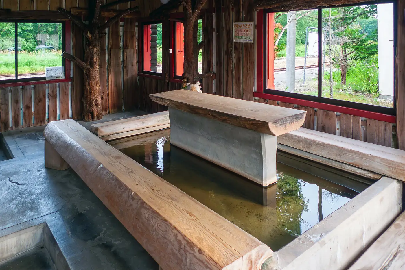 Baño de pies público de agua termal en la estación de Kawayu Onsen, en Hokkaido, con bancos de madera