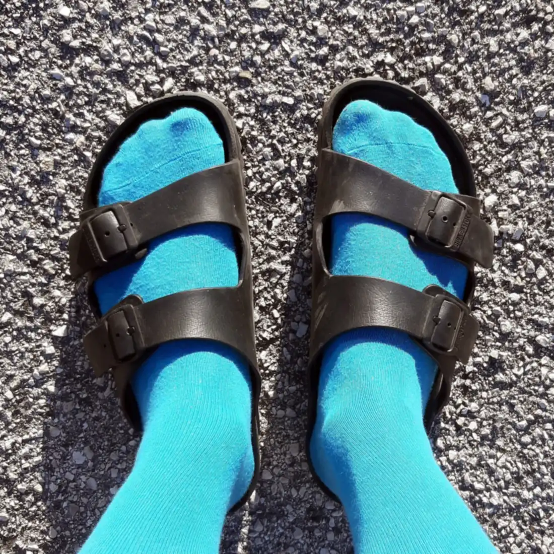 Pies con calcetines azules y sandalias negras de dos tiras