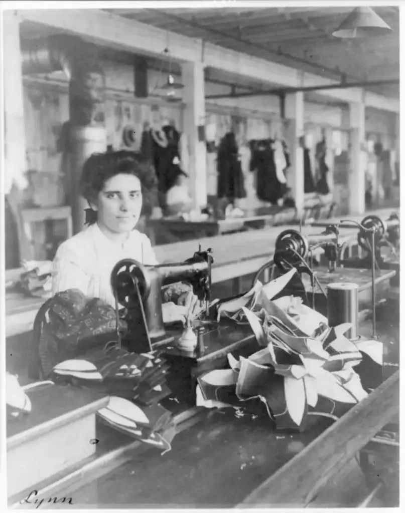 Mujer cosiendo forros de zapato con una máquina de coser en una fábrica de calzado de Lynn (Massachusetts) en 1895