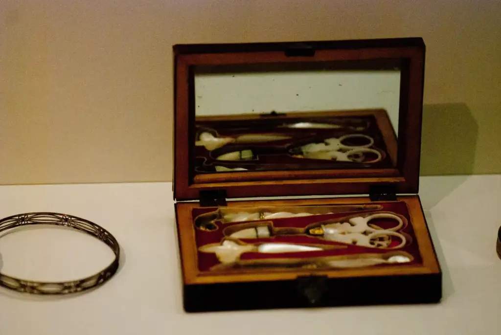Estuche antiguo de manicura con tijeras y útiles de metal en una caja de madera forrada, expuesto en Leipzig