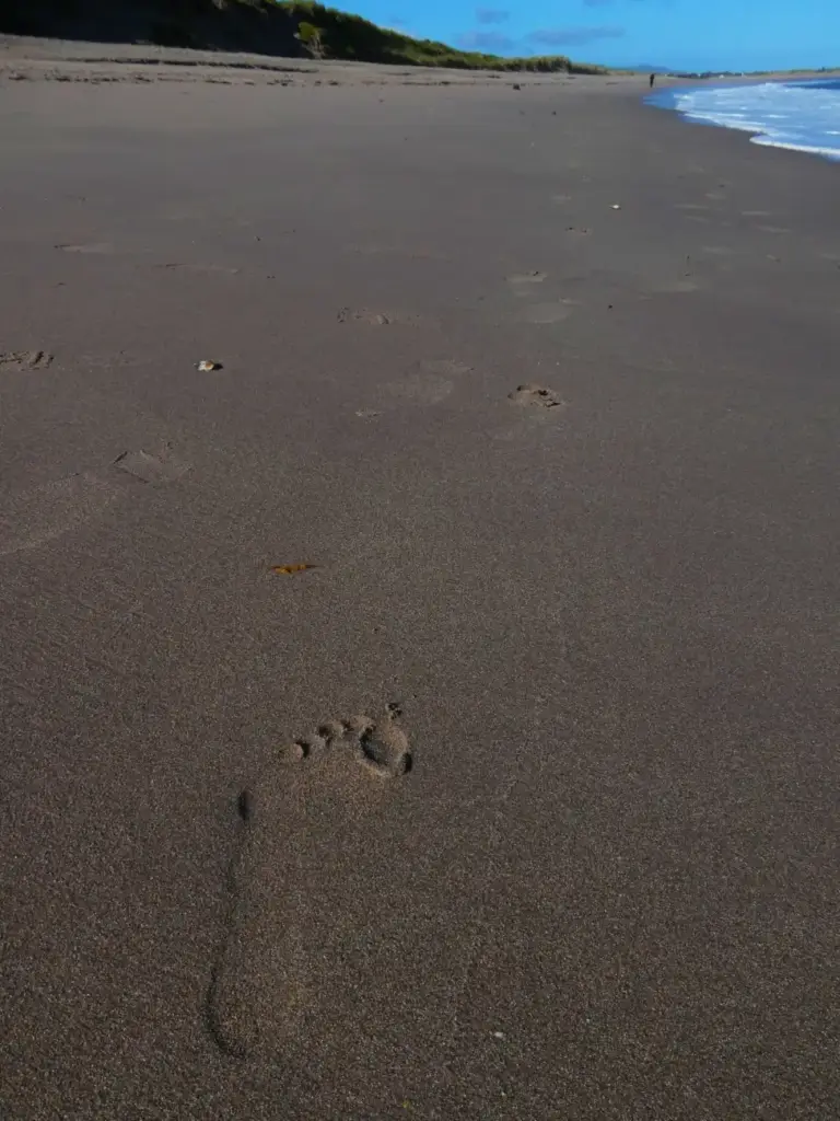 Huella de un pie descalzo en la arena de una playa de Irlanda, con el talón, el arco y los dedos marcados