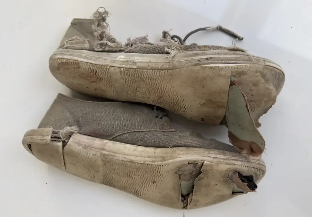 Soles of worn canvas sneakers, worn through at the toe and heel