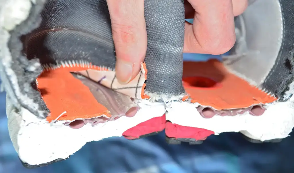 The rear half of a worn running shoe cut in half, showing the midsole foam and the rubber outsole