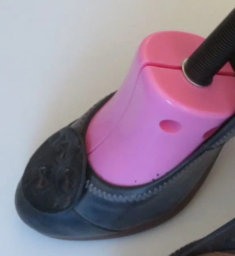 Zapato de salón de piel con un ensanchador de plástico rosa metido en la punta