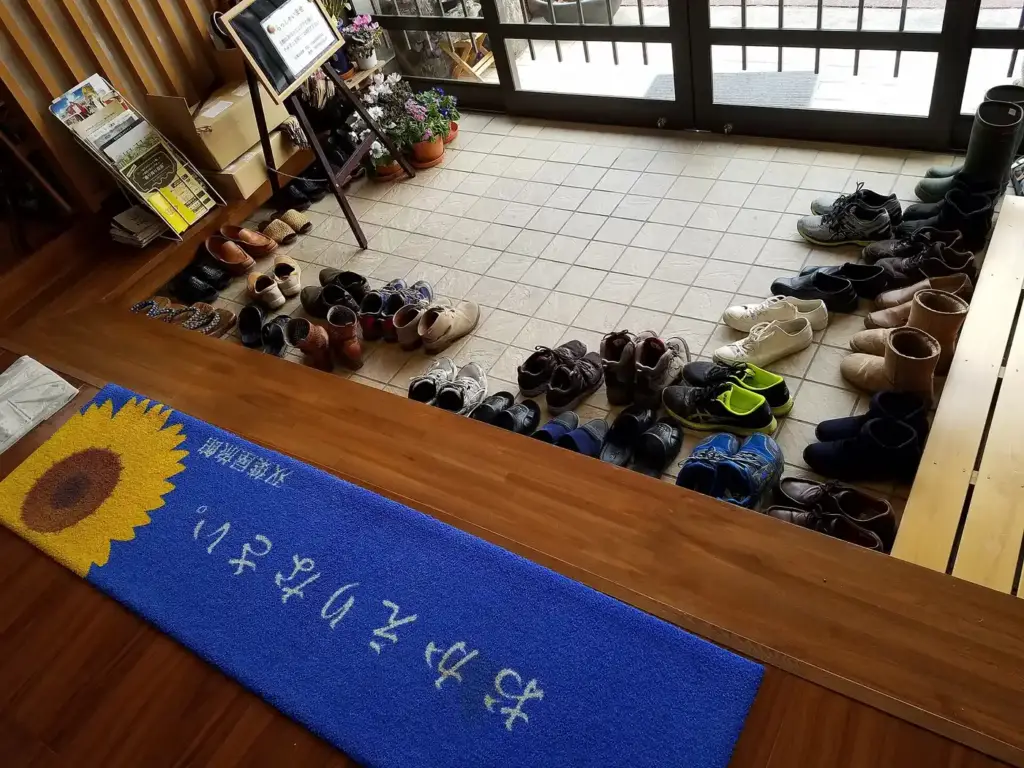 Zapatos de huéspedes alineados en la entrada de un ryokan, un alojamiento tradicional japonés, en Minamisoma