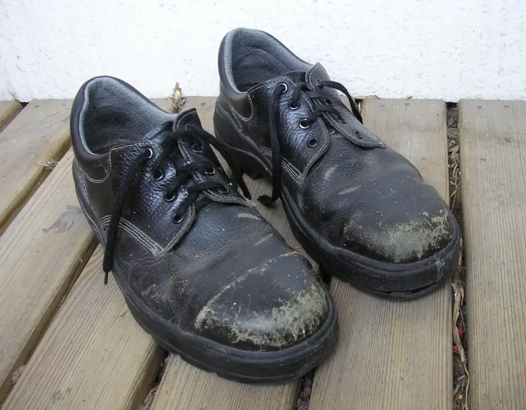 Zapatos de seguridad usados en los que el desgaste de la piel deja ver la forma de la puntera